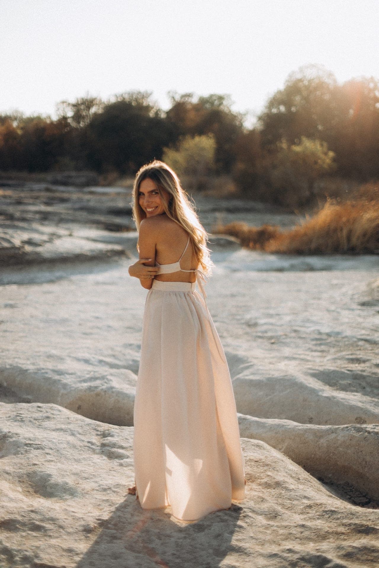 Julia at golden hour by the water, turned toward the light.