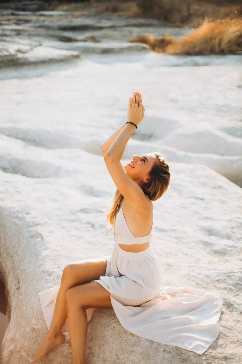 Julia sitting on a rock by the river, one arm raised overhead