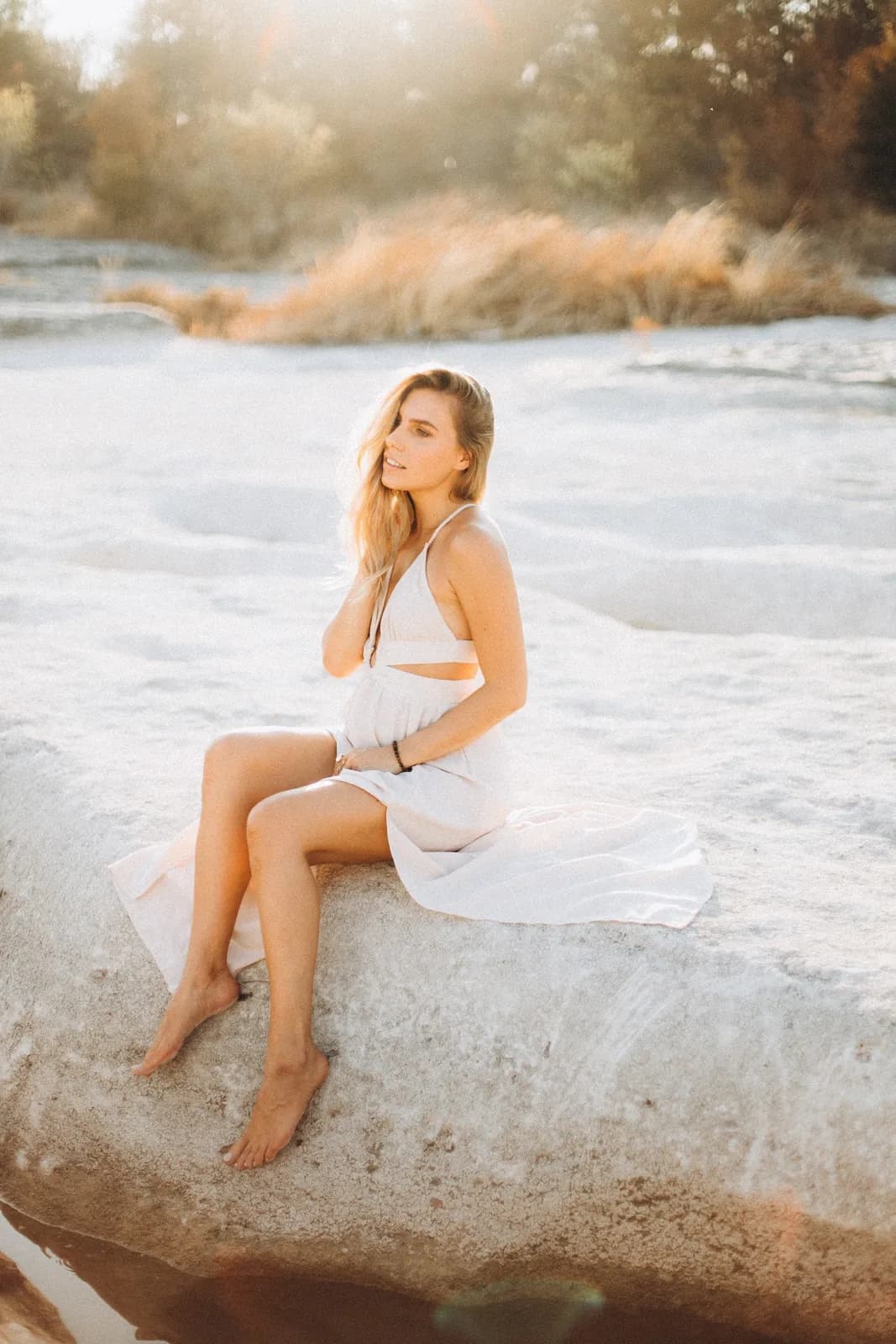Julia sitting on a limestone ledge by the river at sunset
