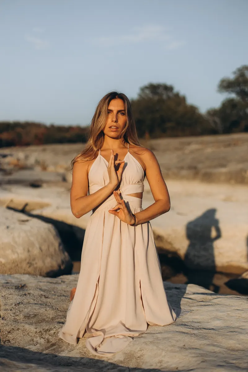Julia standing on the limestone riverbed, hands resting at her chest