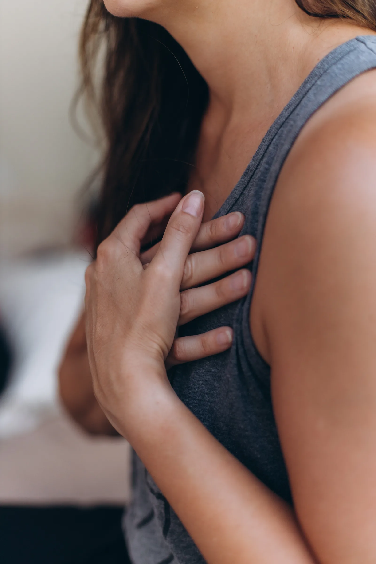 A hand resting at a woman's shoulder, close and quiet