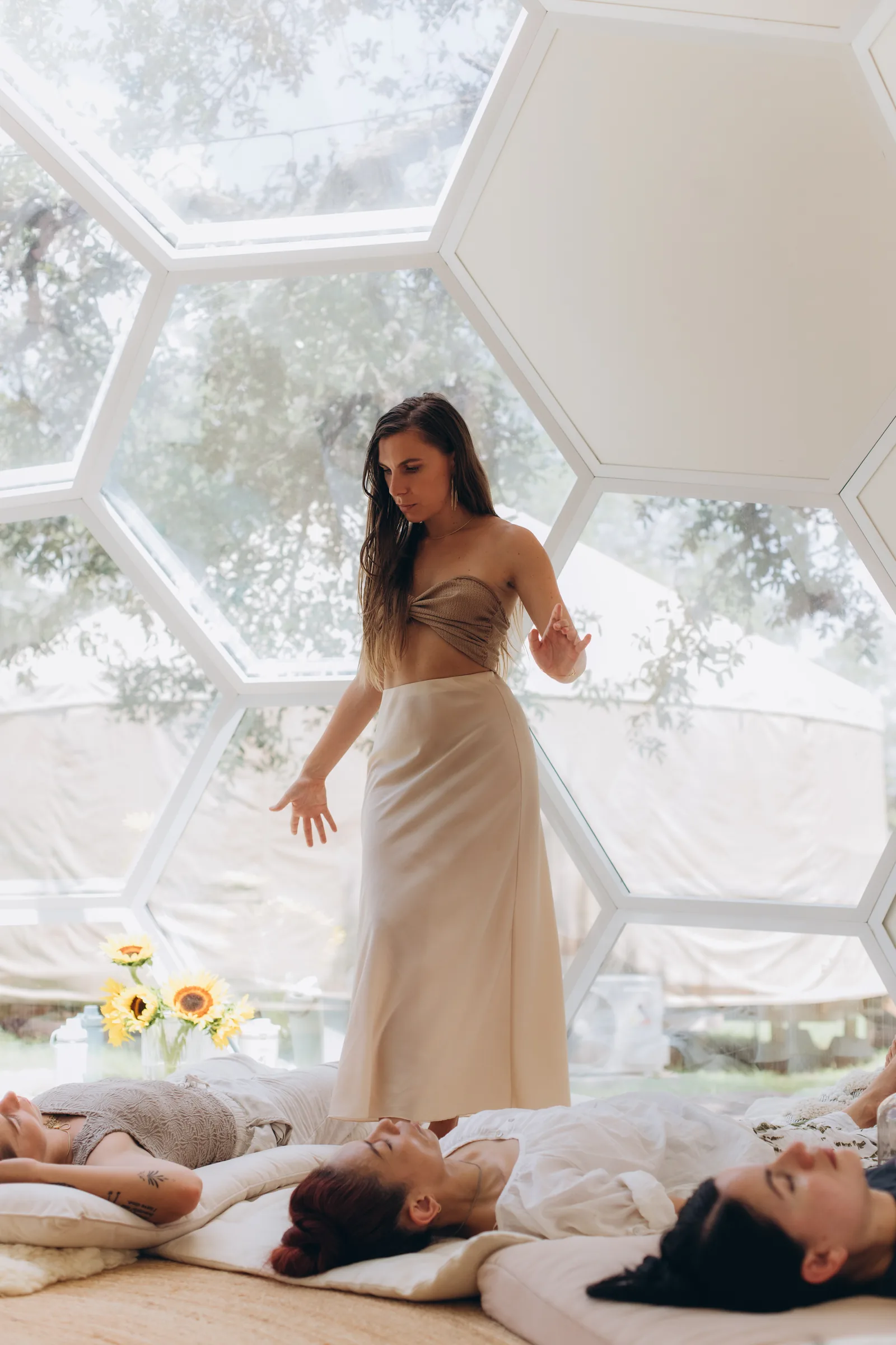 Julia standing in the dome beside sunflowers while the group rests on the floor.