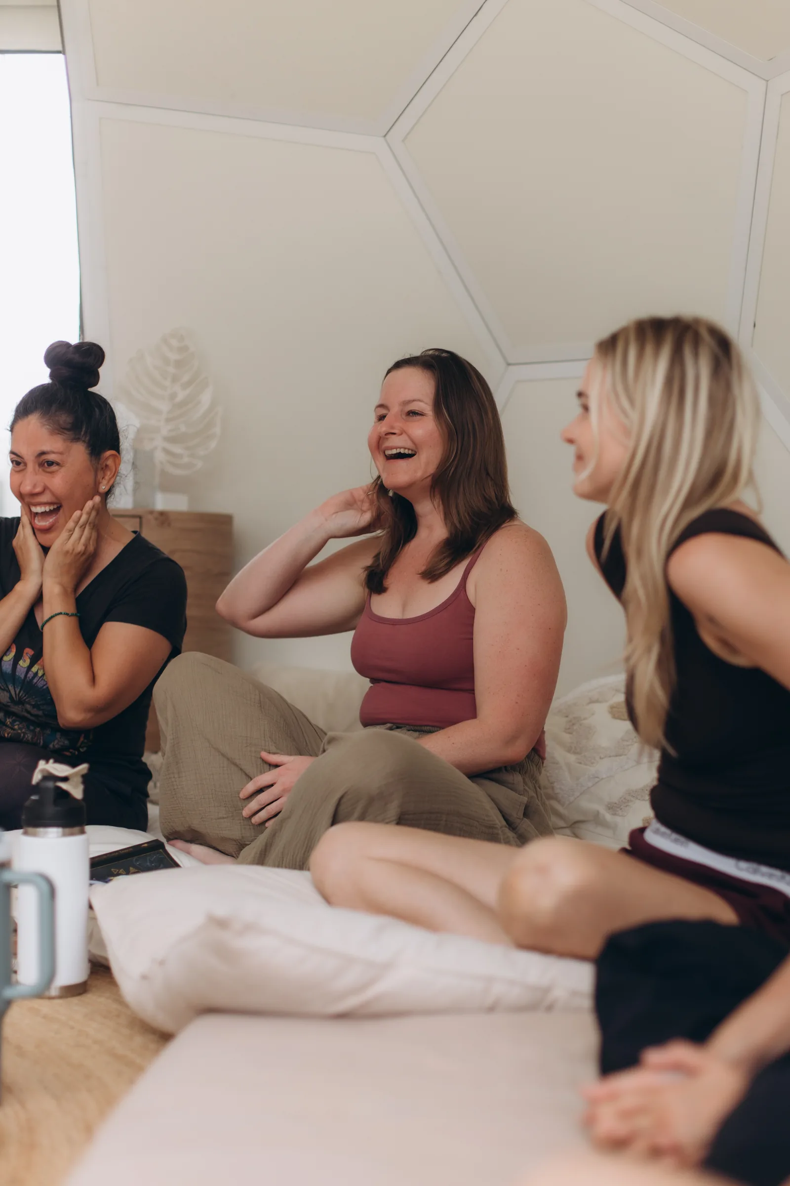 Three women laughing together on the cushions