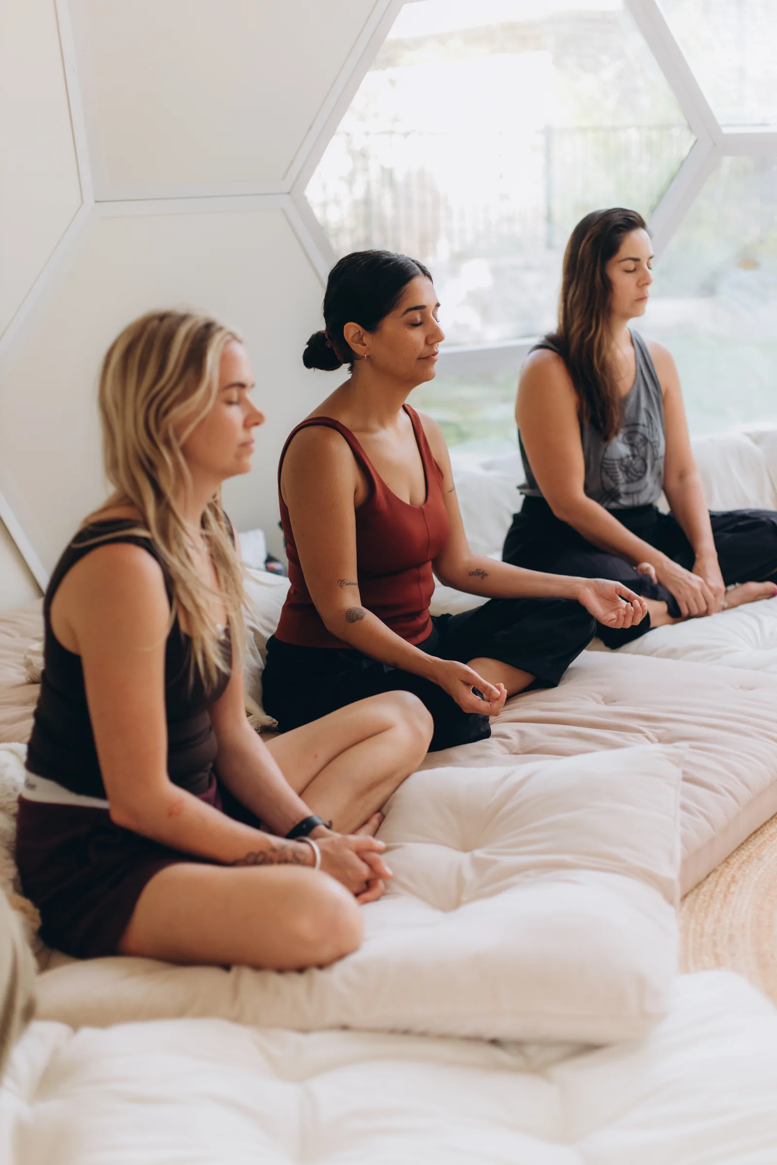 Three women seated in meditation along the dome windows