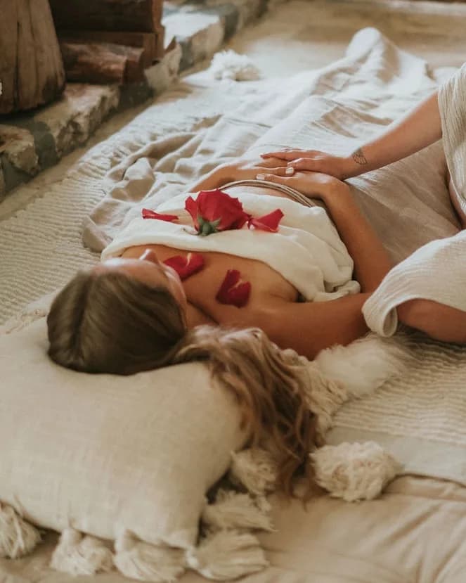 A woman receiving a womb healing session in warm candlelight.
